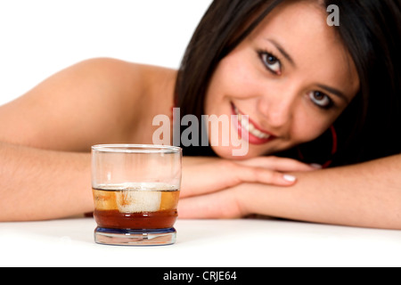 Jeune femme brune assise devant un verre avec le menton sur ses mains avec un sourire Banque D'Images