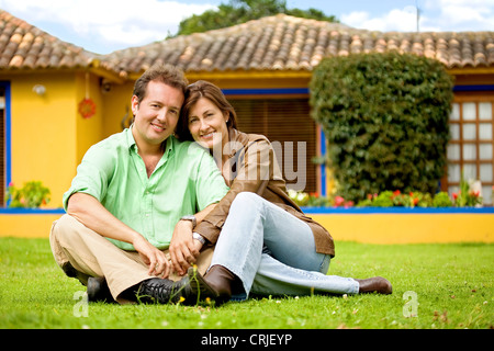 Couple heureux à l'extérieur de leur maison sur une journée ensoleillée à très heureux et détendu - les deux smiling Banque D'Images