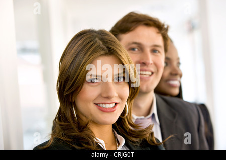 Trois jeunes gens d'affaires debout derrière eux avec un sourire optimiste Banque D'Images