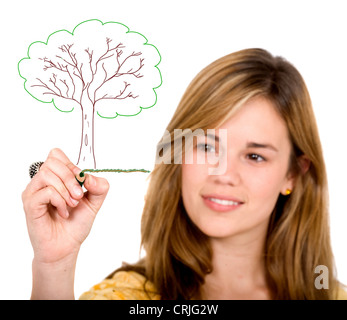 Light Brown young girl drawing un arbre dans un pré sur une vitre en face d'elle à l'aide de crayons Banque D'Images