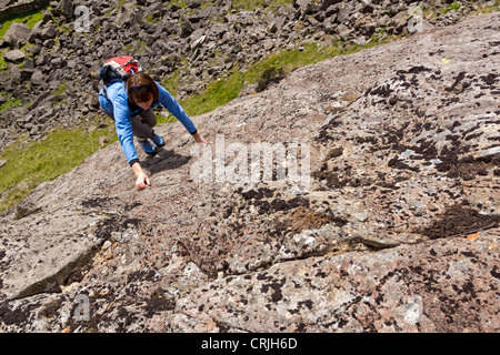 Une femme monte un scrambler rock section raide de rock sur une ruée (le lapin foulé) jusqu'Gillercombe Crag, Lake District. Banque D'Images