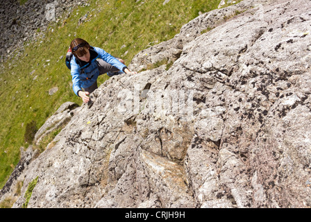 Une femme monte un scrambler rock section raide de rock sur une ruée (le lapin foulé) jusqu'Gillercombe Crag, Lake District. Banque D'Images