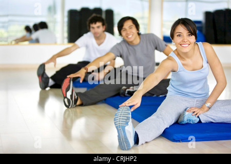 Les gens qui font des exercices d'étirement sur le sol dans la salle de sport Banque D'Images