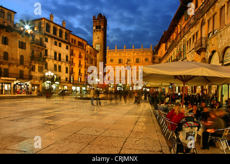 Piazza delle Erbe avec Torre del Gardello et touristes dans un cafés-terrasses à l'heure bleue, Italie, Vénétie, Vérone Banque D'Images