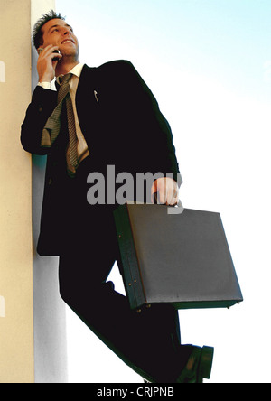 Businessman holding briefcase and talking on phone Banque D'Images