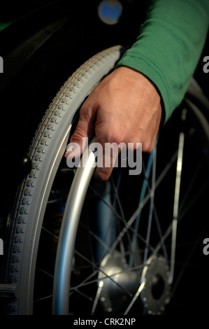 Un gros plan de la main d'un utilisateur de fauteuil roulant, à l'aide de sa main pour déplacer le fauteuil roulant. Banque D'Images