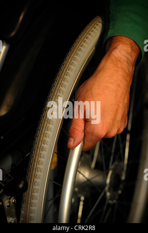 Un gros plan de la main d'un utilisateur de fauteuil roulant, à l'aide de sa main pour déplacer le fauteuil roulant. Banque D'Images