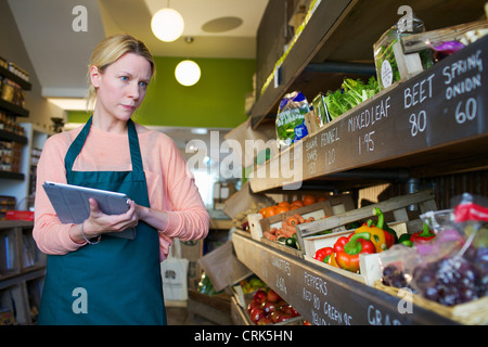 Grocer using tablet computer in store Banque D'Images