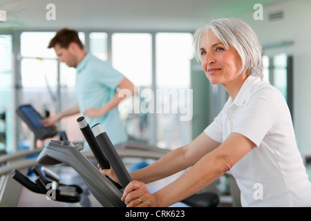 Femme plus âgée à l'aide de tapis roulant dans une salle de sport Banque D'Images