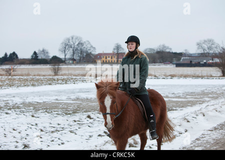 Woman riding horse on snowy path Banque D'Images