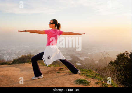 Woman stretching on hilltop Banque D'Images