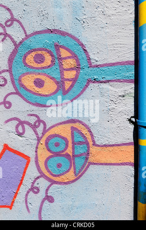 Deux visages de sourire espiègle peint à la bombe sont latéralement sur un mur rempli de graffitis au centre-ville d'Aberdeen, Washington. Banque D'Images