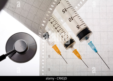 Un stéthoscope et injections allongé sur un électrocardiogramme. Banque D'Images