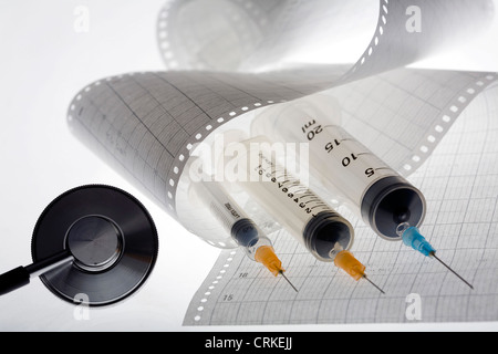 Un stéthoscope et injections allongé sur un électrocardiogramme. Banque D'Images