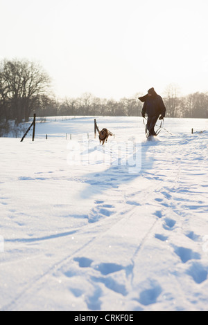 Man Walking dog in snowy field Banque D'Images
