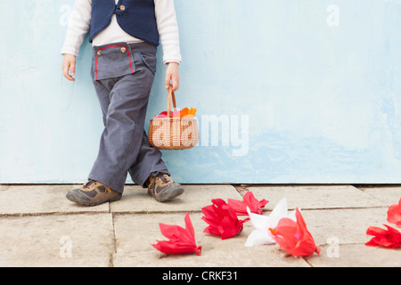 Boy holding panier de fleurs en papier Banque D'Images