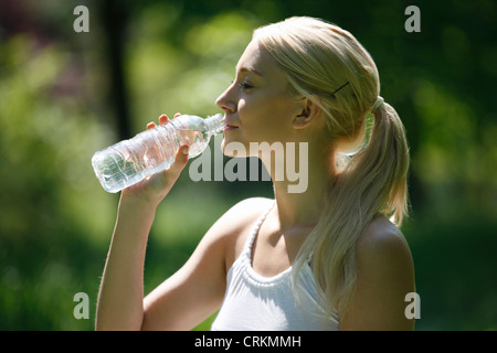 Une jeune blonde boire une bouteille d'eau, Close up Banque D'Images