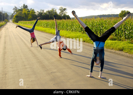 L'été est si amusant : trois enfants n'roues latérales sur un chemin rural Vermont à côté d'un champ de maïs, USA Banque D'Images