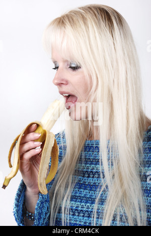 Femme blonde manger une banane Banque D'Images