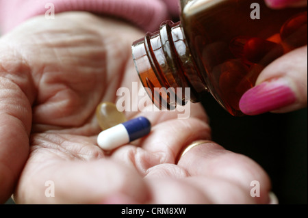 Part d'une femme âgée de servir un petit assortiment de pilules sur la paume de sa main. Banque D'Images