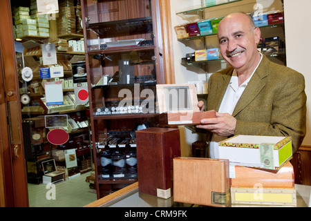 Portrait d'un heureux propriétaire montrant boîtes de cigares en magasin Banque D'Images