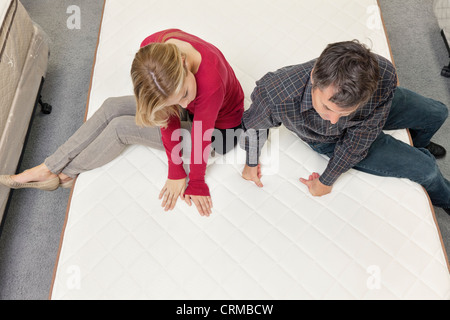 Amis assis sur le matelas in furniture store Banque D'Images