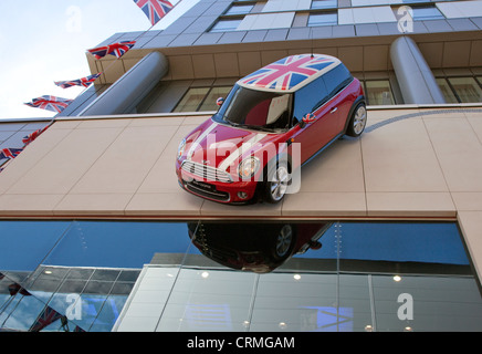 Voiture Mini Cooper coincé sur le côté du bâtiment de l'atelier Mini, Westfield Stratford, London Banque D'Images