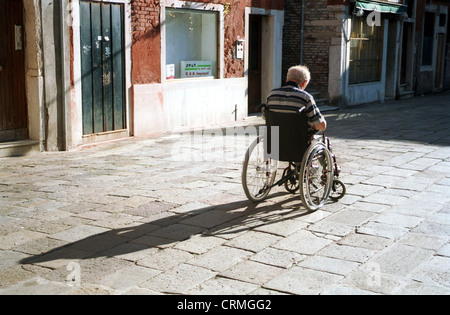 Un vieil homme se repose dans son fauteuil roulant, et profiter du soleil Banque D'Images