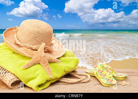 Sac de plage avec une serviette et chapeau de soleil donnant sur l'océan Banque D'Images