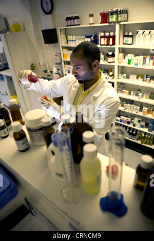 Un pharmacien se déverse un liquide rouge dans un cylindre gradué. Banque D'Images