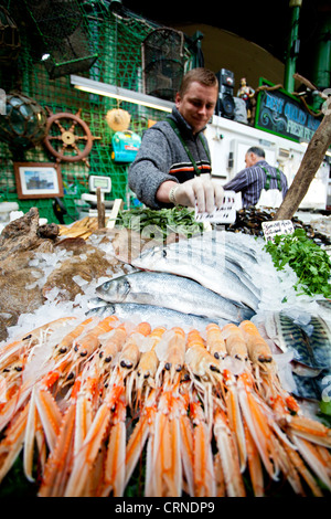 Un poissonnier pose le thon frais et des crustacés pour la vente d'un décrochage à Borough Market. Banque D'Images