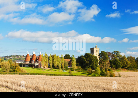 Vue sur un champ de foin vers l'église du village et maisons oast à Horsmonden. Banque D'Images