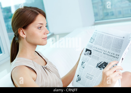 Dame d'affaires attrayant avec un journal d'être absorbé dans ses pensées Banque D'Images