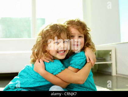 Portrait of cheerful twin sisters hugging and smiling at cam Banque D'Images