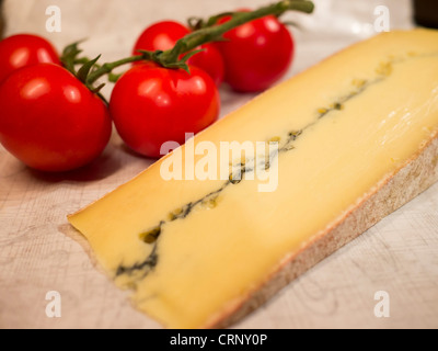 Une tranche de morbier et un tas de tomates mûres. Morbier est une semi-soft le lait de vache, du fromage de France. Banque D'Images