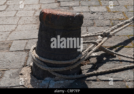 Cordes d'amarrage attachées à un vieux bollard de fer sur un quai de port, Sicile, Italie Banque D'Images