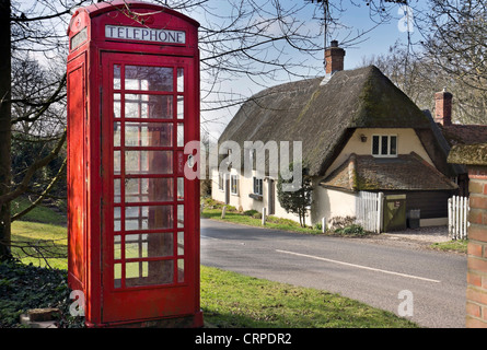 Téléphone traditionnel fort en face d'une chaumière dans le village de Brent Pelham. Banque D'Images