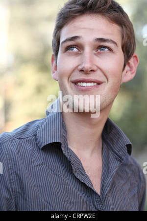 Beau jeune homme décontracté tout en souriant légèrement à l'extérieur Banque D'Images