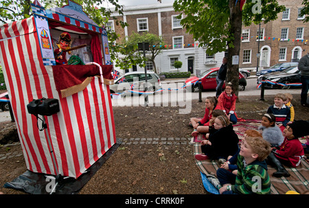 Les enfants de regarder un spectacle de marionnettes Punch & Judy à l'extérieur dans le cadre d'un festival Banque D'Images