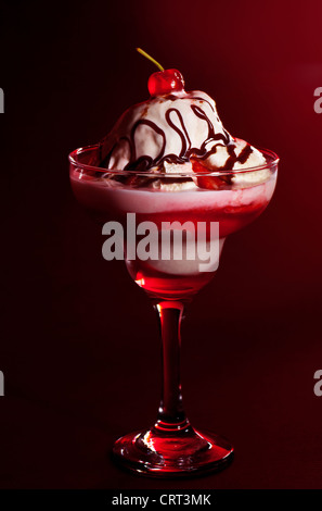 Fruitée froide la crème glacée, yogourt glacé à la vanille savoureux la vie encore isolé sur fond rouge, confiture de cerise et de chocolat liquide Banque D'Images