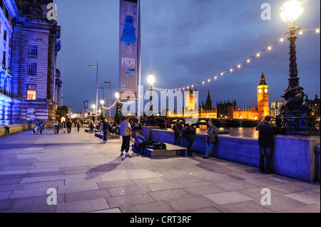 LONDRES, Angleterre — L'emblématique palais de Westminster, qui abrite le Parlement britannique, se dresse majestueusement le long de la Tamise, vue depuis Queen's Way. Son architecture néo-gothique, dominée par la tour de l'horloge abritant Big Ben, est illuminée contre le ciel du soir, reflétant des siècles d'histoire politique britannique. Banque D'Images