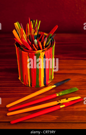Pinceaux multicolores dans un pot recouvert de gouttes de peinture Banque D'Images