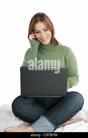 Woman talking on mobile phone in front of laptop Banque D'Images