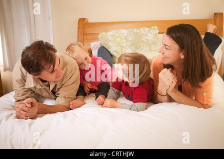 La mère, le père et ses deux enfants sont couchés sur le lit. Banque D'Images