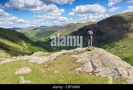 Un randonneur donne sur la vallée de lait aigre-Seathwaite Gill lors d'une journée ensoleillée dans le Lake District, UK. Banque D'Images