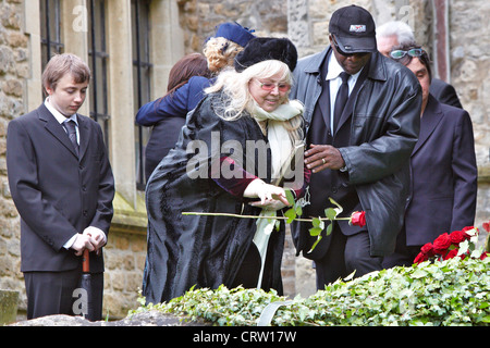 Dwina Gibb (centre), épouse de Robin Gibb, jette de la terre sur le cercueil lors des funérailles de la chanteuse Gee Bee. Banque D'Images