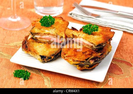 Aubergines panées avec du jambon et du fromage. Recette disponible Banque D'Images