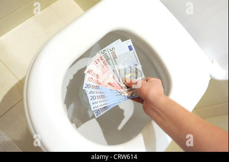 En descendant le panoramique d'une sélection de billets de monnaie euro en 5s 10s et 20s sur le point d'être jeté dans une toilette Banque D'Images