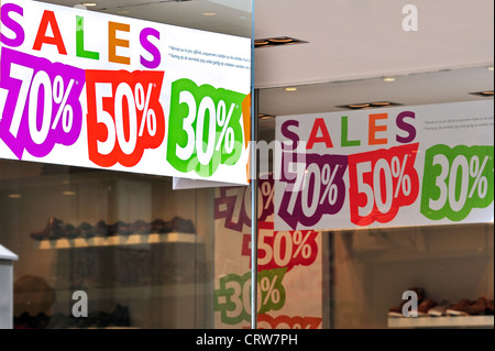 Les chaussures et les panneaux signalant la remise de retenues à la vitrine de magasin de chaussures pendant les soldes d'été dans la rue commerçante Banque D'Images