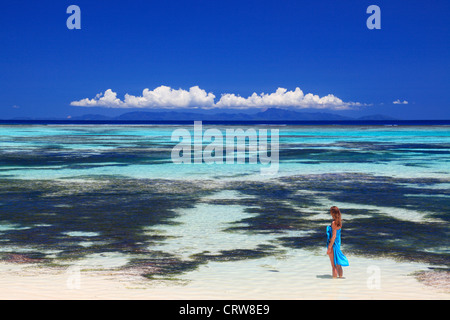 La femme en bleu sarong patauge dans les eaux près de Anse Source d'argent sur La Digue aux Seychelles Banque D'Images